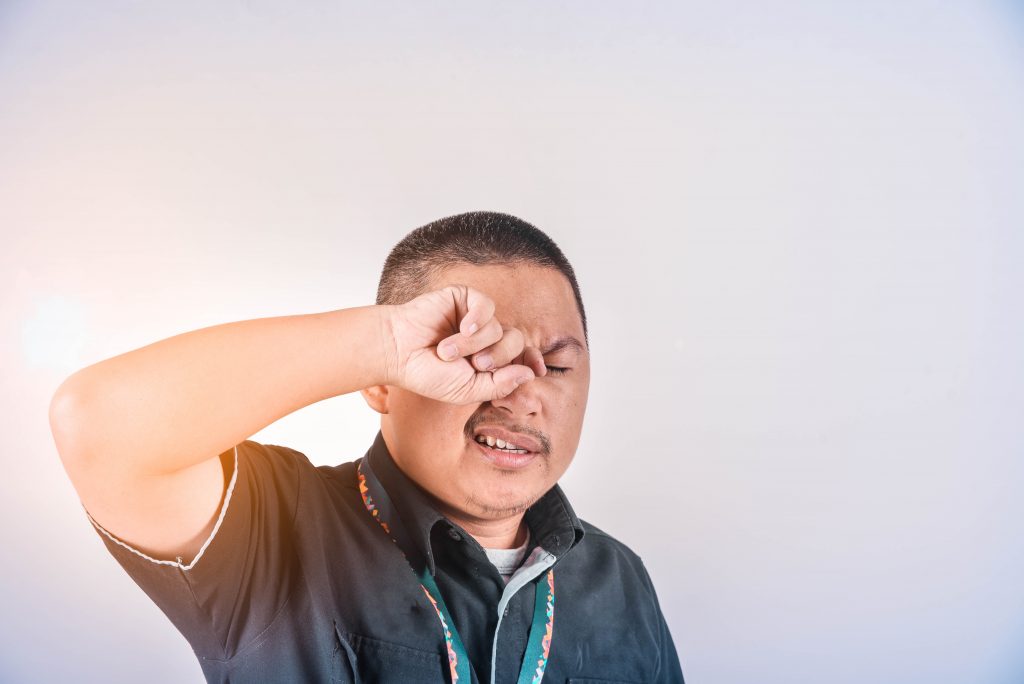 Image of a man rubbing his eyes due to irritation from hayfever