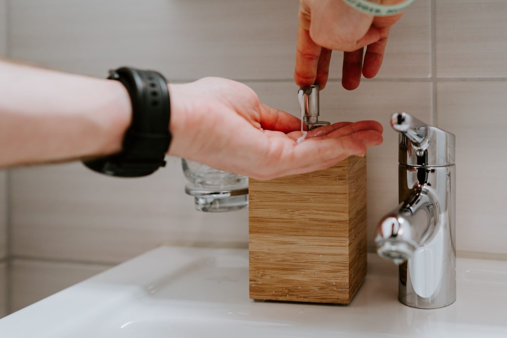 Image of someone using a soap dispenser ready to wash their hands.